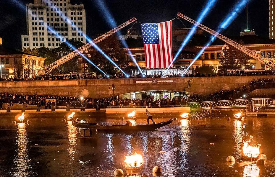 A gondola pass on the river in front a large american flag.