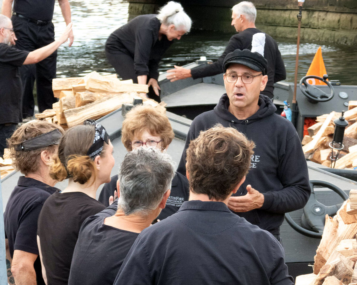 Charlie Stone speaks to other volunteers before a WaterFire event. Photograph by Christian Podzon.
